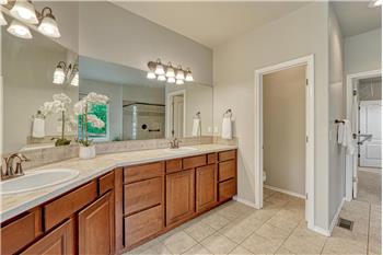 The Primary Bathroom features tile flooring, an expanded dual sink vanity, and mirror.