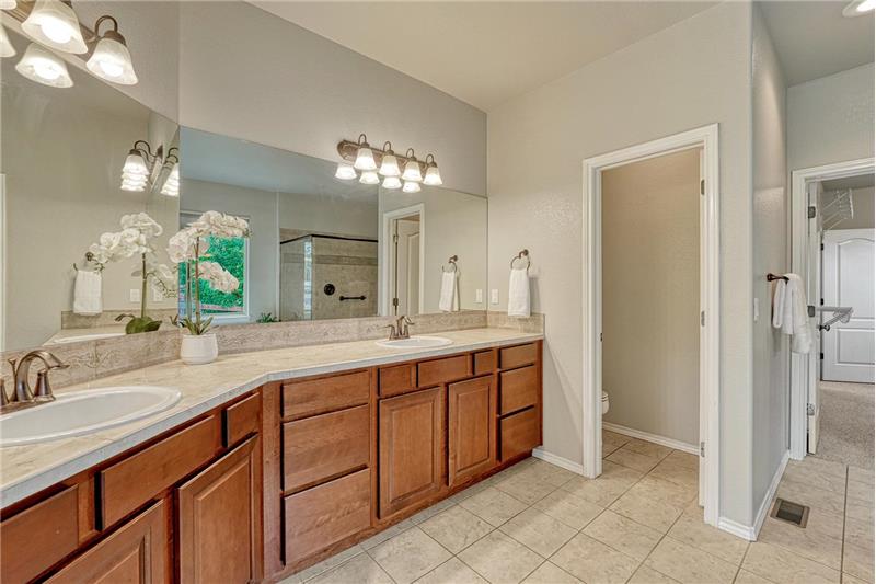 The Primary Bathroom features tile flooring, an expanded dual sink vanity, and mirror.
