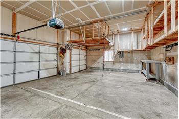 3-car attached garage with custom ceiling storage, work bench, and door opener.