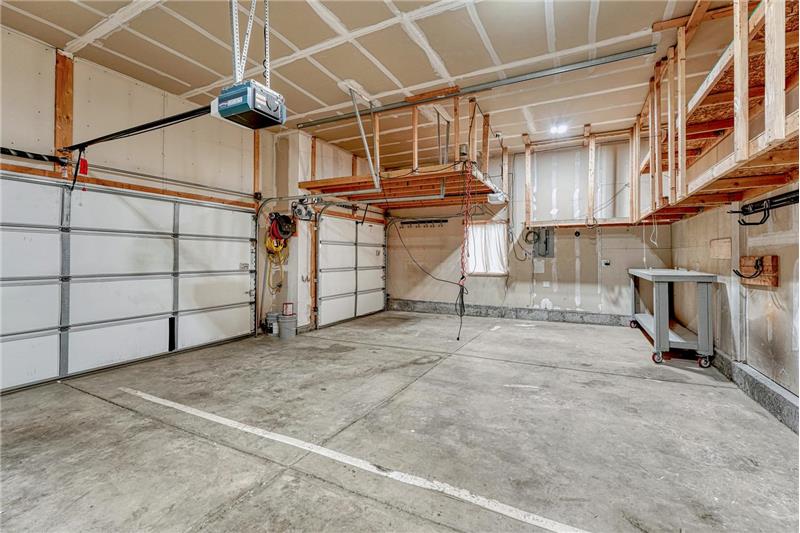 3-car attached garage with custom ceiling storage, work bench, and door opener.