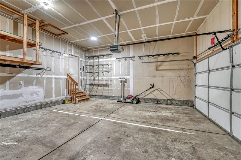3-car attached garage with mounted tool rack and custom storage that stays.