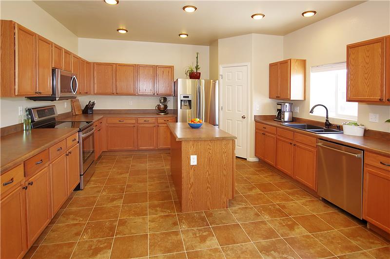 Large kitchen with stainless steel appliances, island, and pantry