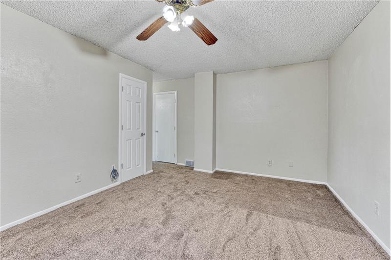Lower level family room with a storage closet and ceiling fan.