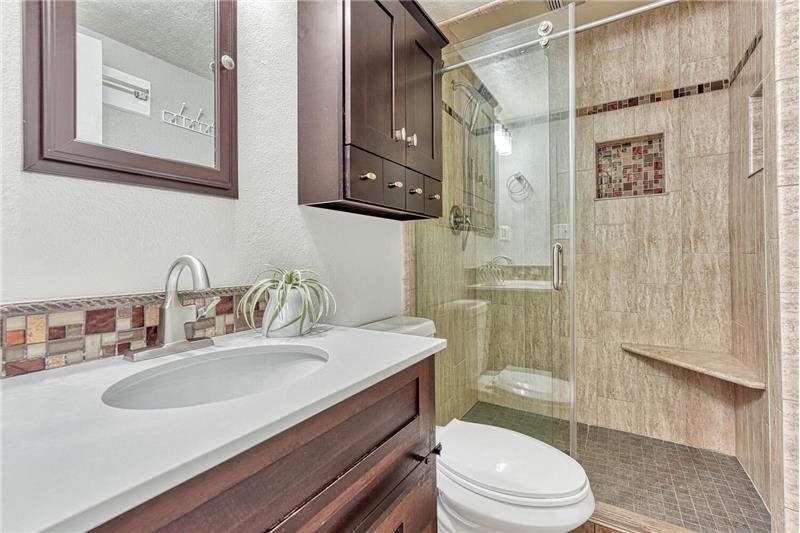 Lower level 3/4 remodeled bath! Frameless shower door, tiled shower with corner shelf and shower niche, and tiled sho