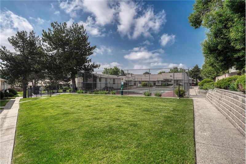 View of grassy area behind townhouse and view of tennis courts