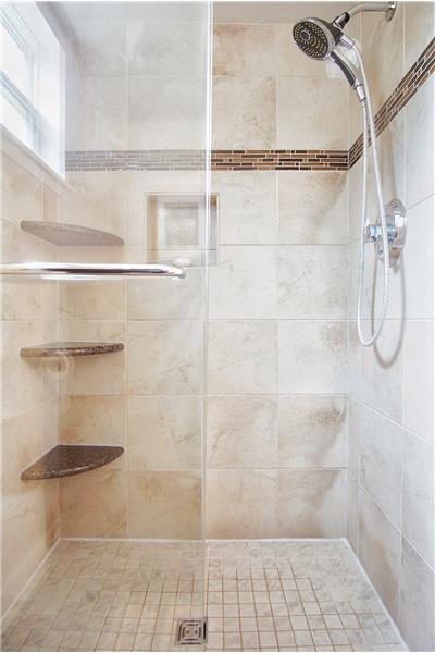 Fully tiled shower enclosure with built-in shelving completes the master bath