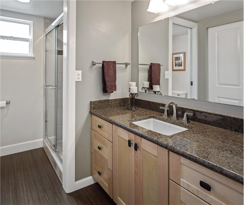 The master bath has been tastefully updated with granite countertop, fully-tiled shower, and sustainable Marmoleum flooring