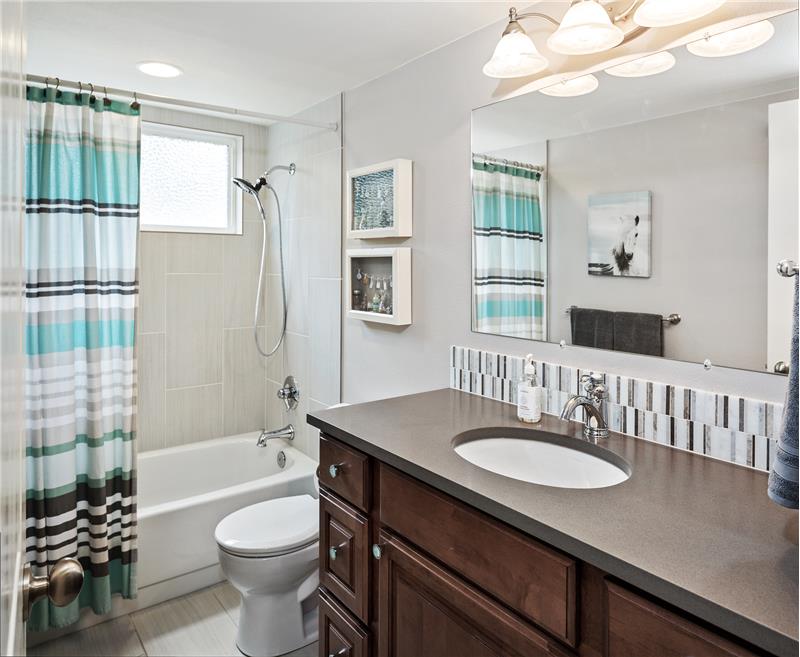 The full bath on the main floor features solid-surface countertop and tile surround bath