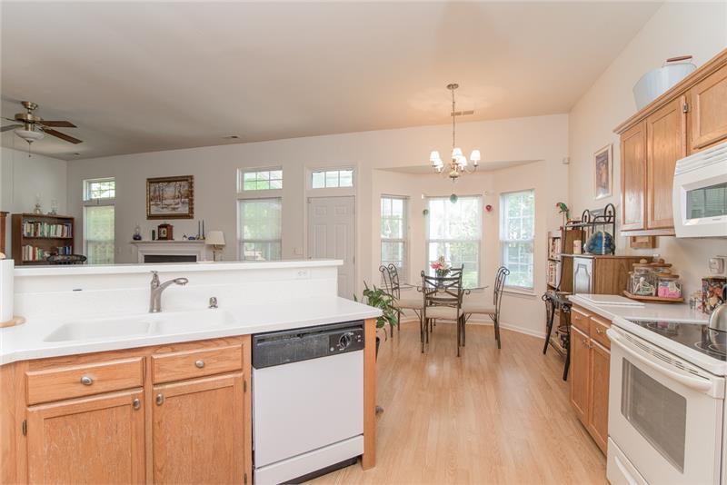 Laminate wood flooring, white countertops and white built in appliances give the kitchen a bright, clean look.