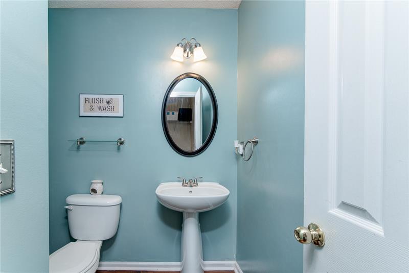 The powder room includes a pedestal sink and classy fixtures.