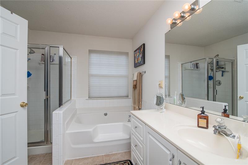 The en suite bathroom includes a large soaking tub, separate shower and dual sinks.
