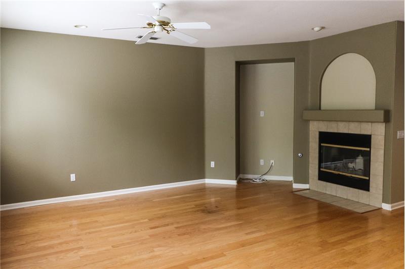 Cozy family room at the back of the house features new paint, ceiling fan and wood burning fireplace with gas starter