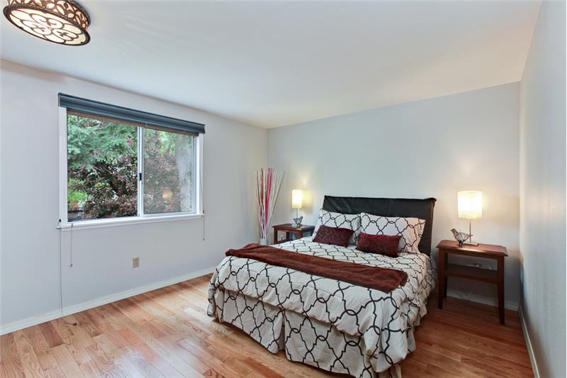 Master bedroom on upper level with hardwood floors and view of the garden. 