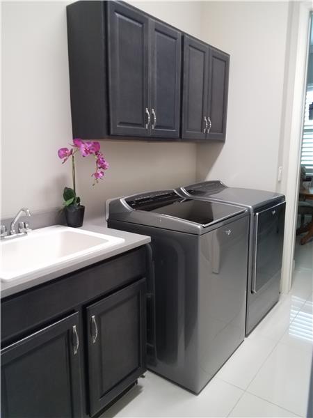 Laundry room has utility sink, cabinets, and storage closet.