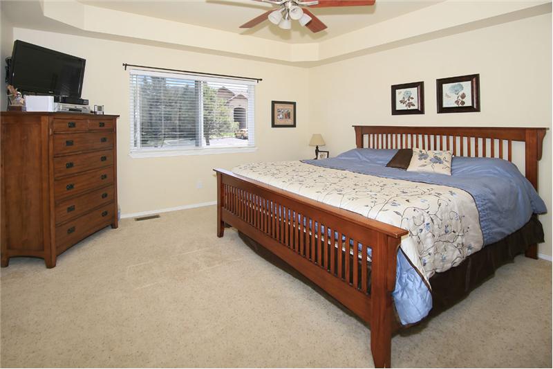 Master bedroom with ceiling fan and tray ceiling.