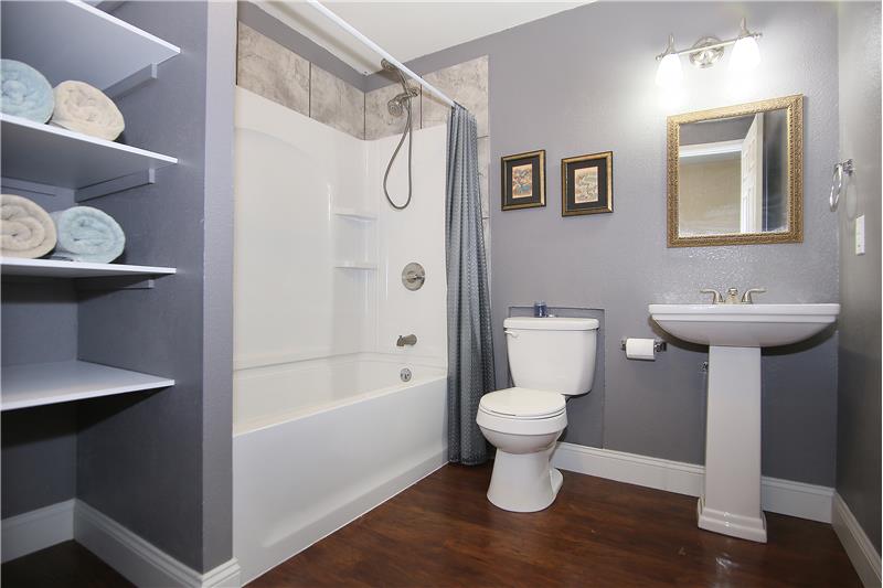 Full bath with pedestal sink and built-in shelving in basement
