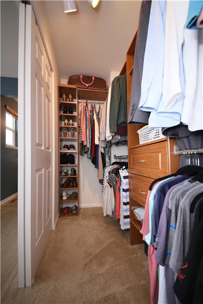 Large closet in master bedroom with a built-in shelving system