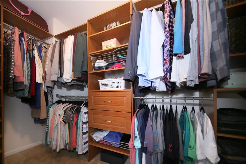 Large closet in master bedroom with a built-in shelving system