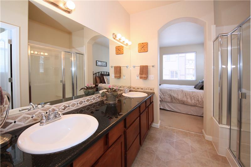 Spacious master bath provides a large shower with bench, a double vanity with a granite counter top, and tile flooring