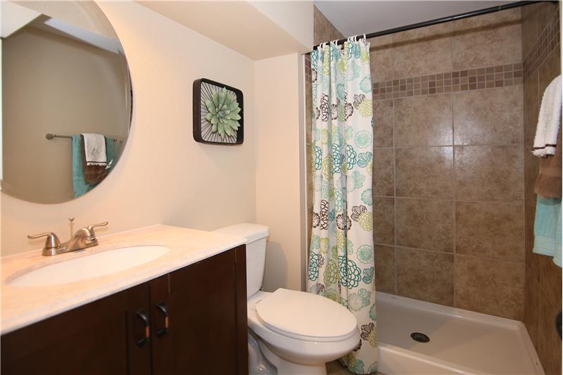 3/4 bath in basement with large tile shower, tile floor, and updated vanity