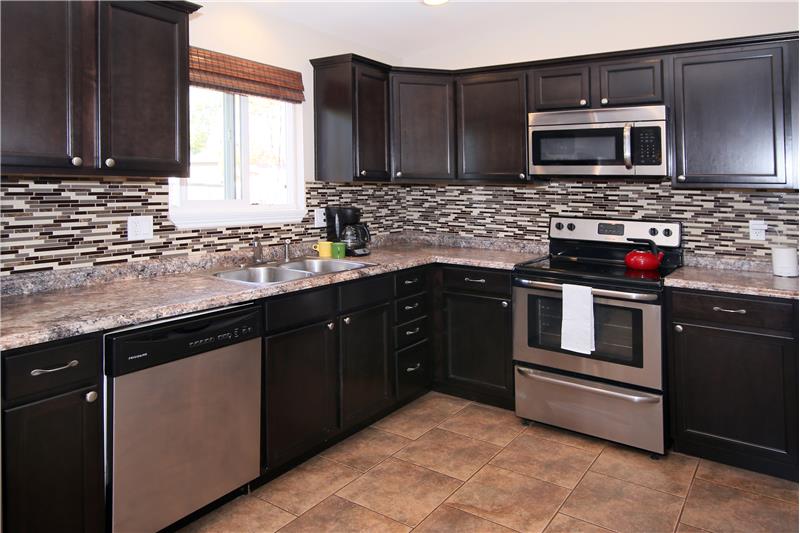 Kitchen with stainless steel appliances, tile flooring, updated cabinets, and tile backsplash