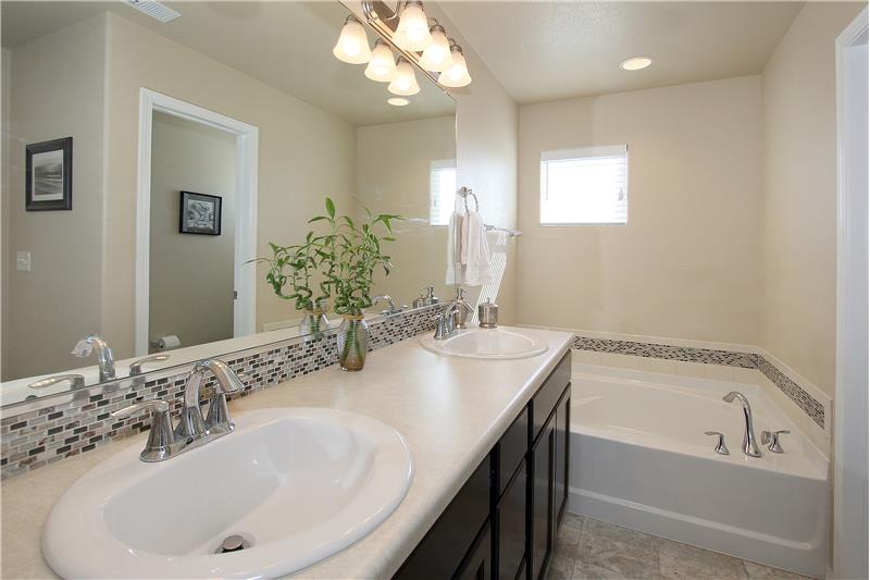Master bath with double sinks, comfort height vanity, and a soaking tub