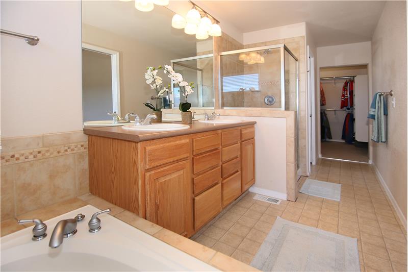 Master bath with double sinks, comfort height vanity, separate shower, and walk-in closet