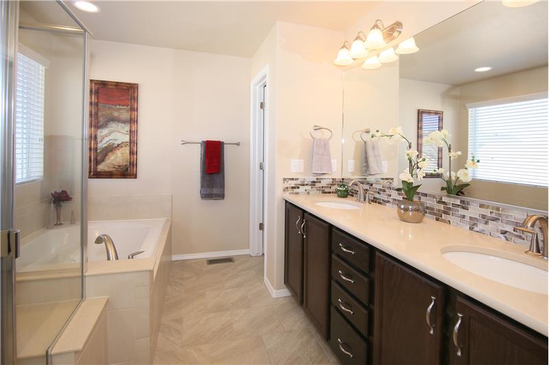 Master bath with double sinks, comfort height vanity, and a soaking tub