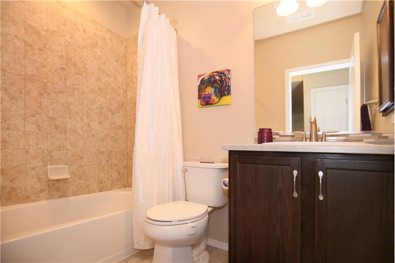 Full bathroom in basement with tile flooring and tile surround
