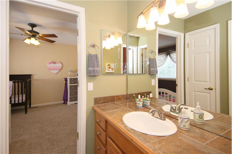 Jack and Jill bath with linen closet, tile flooring, tile counters, and tile bath surround