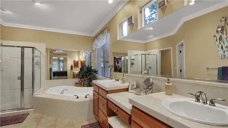 Master bath with double sinks, comfort height vanity, shower, and a soaking tub