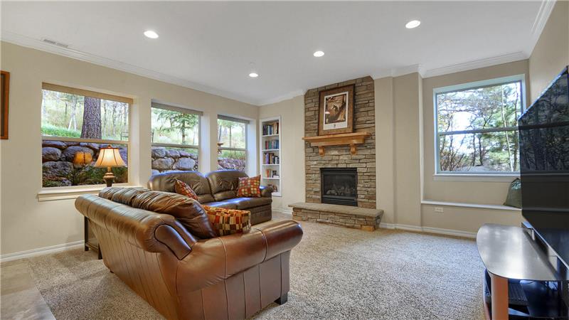 Bright garden level family room with stone gas fireplace, crown molding, and recessed lighting