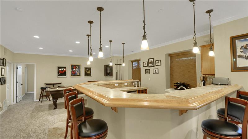 Large wet bar with pendant lighting is perfect for entertaining your guests. Bar stools stay!