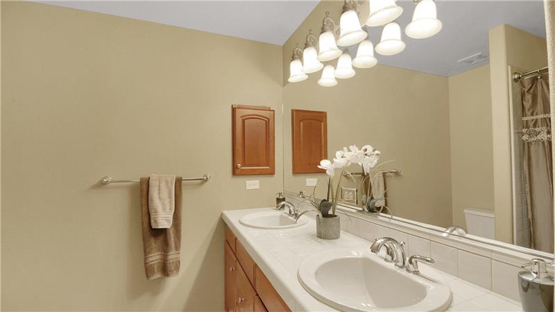 Full bath on upper level with linen closet, double sinks, and a comfort height vanity