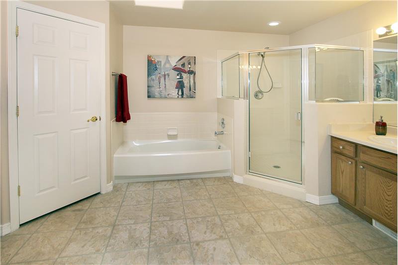 5-piece master bathroom with large shower with bench, skylight, and separate vanities