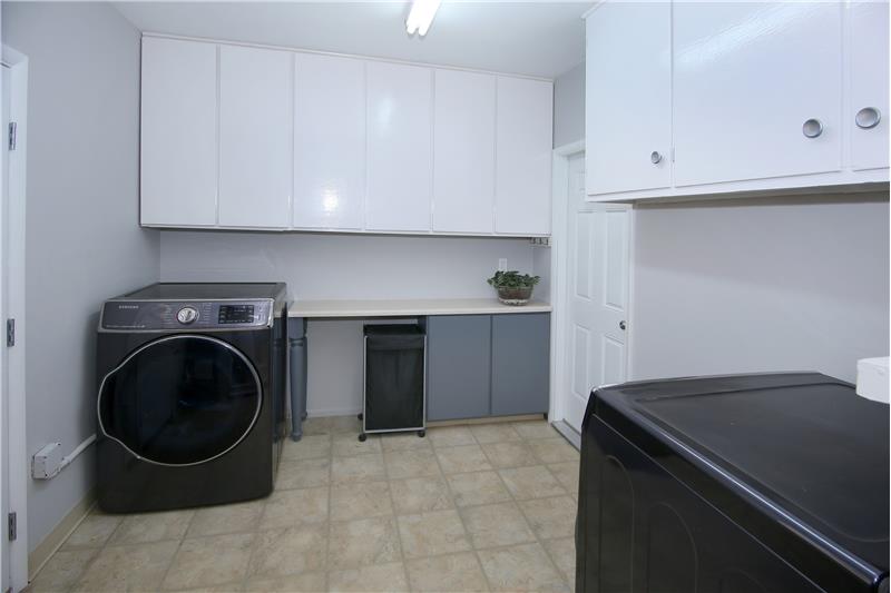 Laundry/Storage area with plentiful cabinets adjacent to the kitchen also provides a walk-out to the garage and a walk-out to th