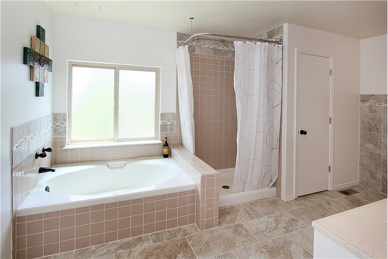 Updated master bath with tile flooring, soaking tub, and separate shower