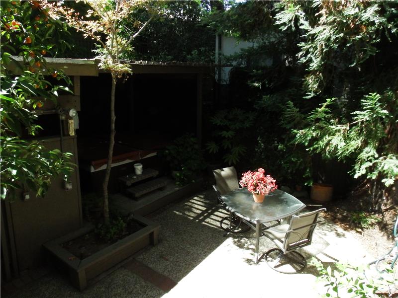 A brick patio and several garden areas are shaded by the beautiful redwoods.