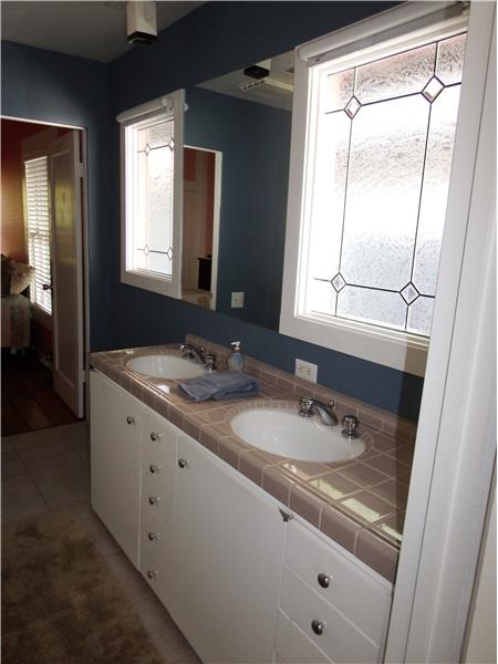 The downstairs bathroom features dual sinks and more natural light shining through the custom lead glass windows.