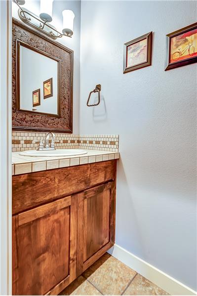 Powder room downstairs off the great room features tiled counter tops and decorative back splash.