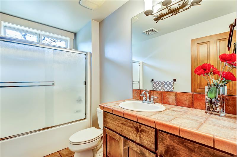 Bright and cheerful guest bathroom with tiled counters and floors.