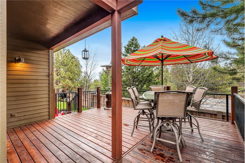 Expansive deck is partially covered surrounded by mature aspen trees and landscaping.