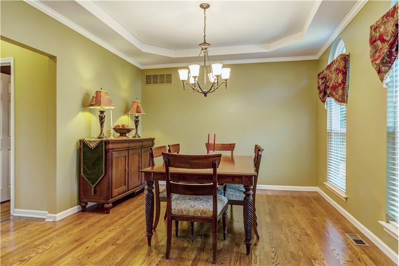 Formal dining room. wood floor, tray ceiling, crown molding, wood blinds and palladian windows.