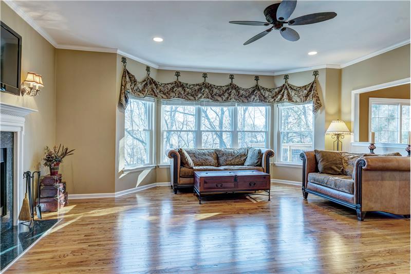 Family room with wood floor, 5 bay window, fireplace, crown molding and recessed lights.