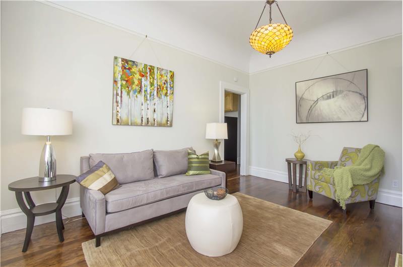 A spacious living room, filled with wonderful features like a quaint window seat and Victorian light fixtures that heap characte