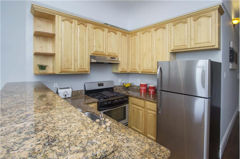Granite countertops, stainless appliances and custom stained cabinetry complete the look in this open plan space.