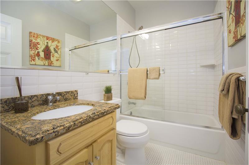 The recently remodeled bathroom that carries a bathtub and shower combo, surrounded by sleek white beveled subway tiles.