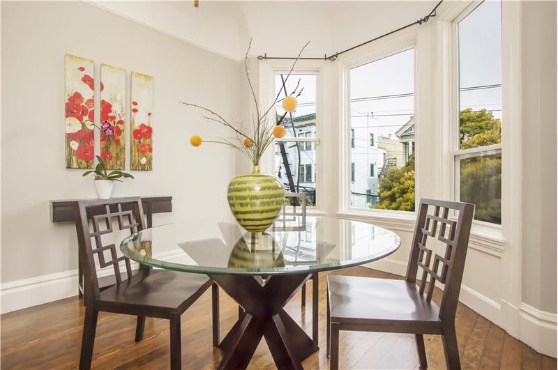 Plenty of natural light flows through large bay windows framed in original casework, making this dining area a perfect spot for 