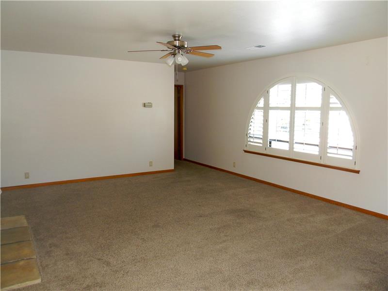 Plantation shutters cover the windows in the living room. The door at the end of the picture leads to the 2nd master bedroom.