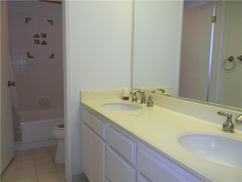 The shower/tub and toilet are separated from the dual sink vanity in the guest bathroom